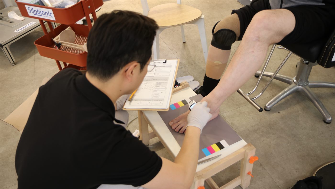 하퇴 의족을 착용한 고객님의 반대쪽 발 피부색을 컬러차트 위에서 측정하는 전문가