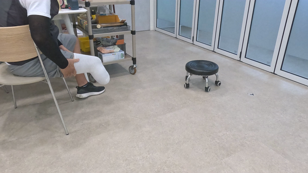 의자에 앉아 무릎 아래 환부를 감싼 채 본뜨기를 기다리는 고객님