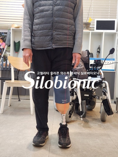 휠체어 앞에서 하퇴 의족을 착용하고 선 모습