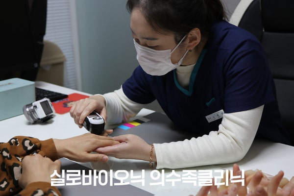 직원이 E-SKIN 스캐너로 고객의 손 피부색을 측정하는 모습