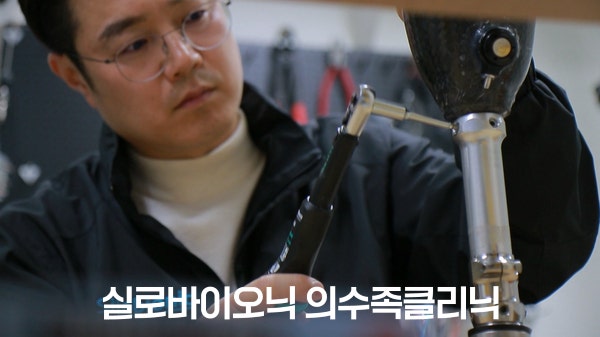 다리 의족의 연결 부품을 공구로 조정하는 제작 전문가