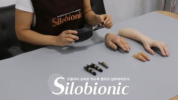 직원이 티타늄 손가락과 실리콘 의수 샘플을 살펴보는 모습