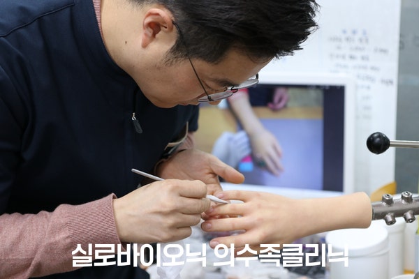 제작 담당자가 실리콘 손 의수의 손끝을 가는 붓으로 다듬는 모습